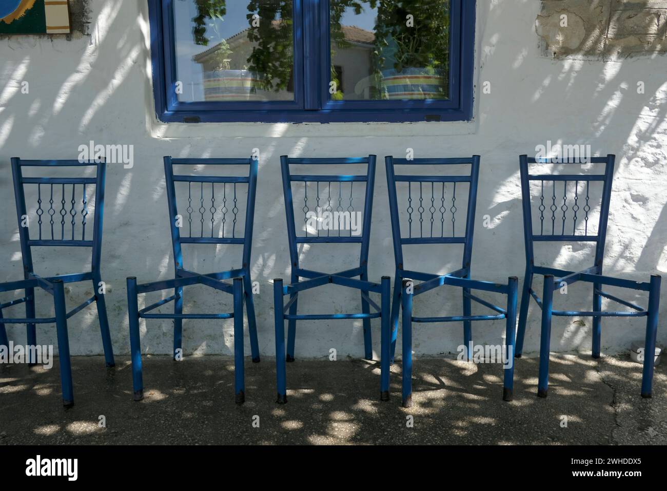 Griechenland, Parga, leere blaue Stühle ohne Sitzkissen, ein ruhiger Nachmittag Stockfoto