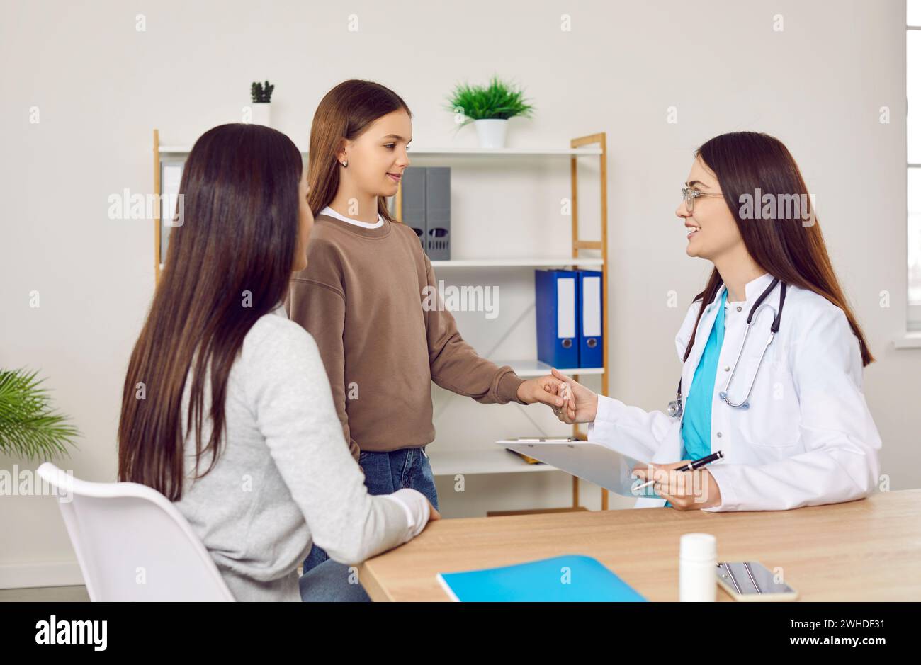 Fürsorgliche weibliche Ärztin nimmt Hand von aufgeregtem Teenager Mädchen, das vor der medizinischen Untersuchung besorgt ist. Stockfoto
