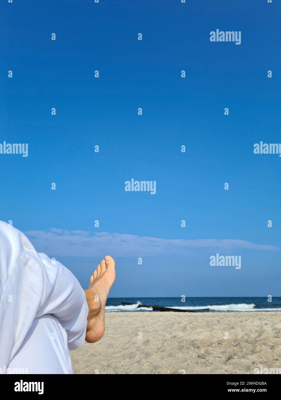 Weiße Leinenhose mit Frauenfuß im Vordergrund, Blick auf das Meer und den blauen Himmel, Markgrafenheide, Ostsee, Deutschland Stockfoto