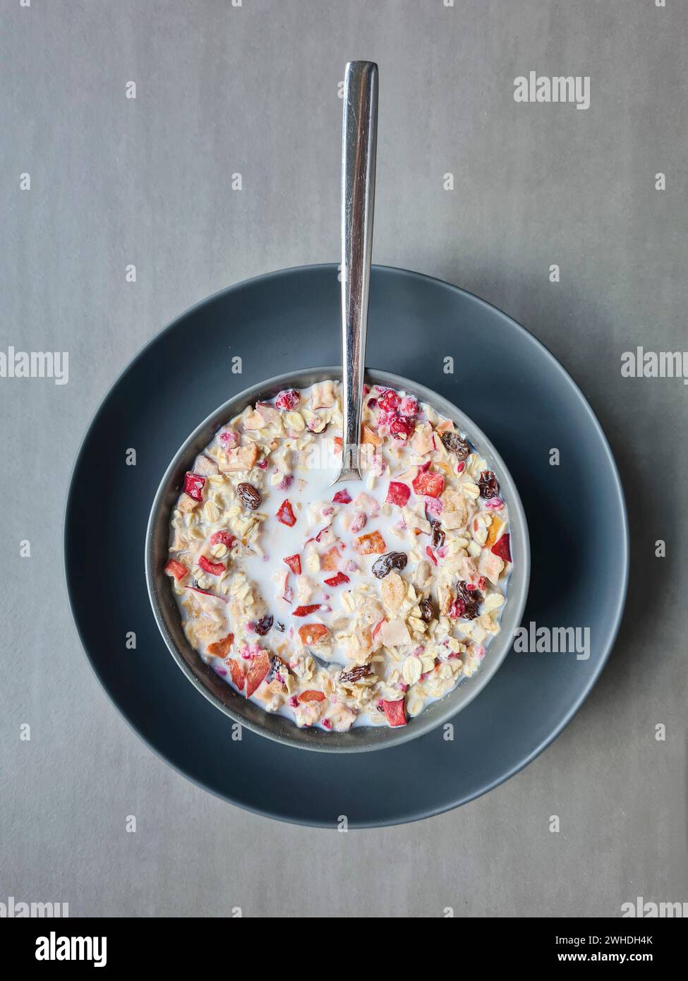 Müsli mit Milch in einer Schüssel zum Frühstück, Obstmüsli mit Getreide und Obst, Löffel Stockfoto