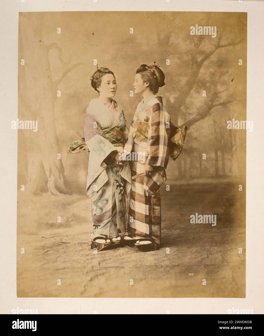 Zwei japanische Frauen in Kimonos, durchgehendes Studio-Porträt mit Hintergrund, stehend, gegenüberstehend, Hände haltend. 1877 ....Japan handkoloriert mit Aquarell-Fotografie um die 1870er Jahre Stockfoto