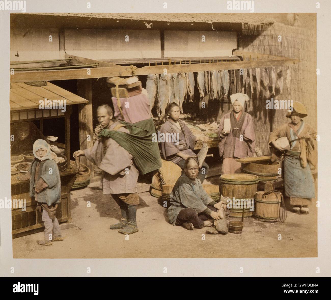 Außenansicht des Fischmarktes mit mehreren Personen, Einkäufern und Händlern, die Fische halten, auch ein Portier mit großem Bündel auf dem Rücken, und eine Frau, die Instrument spielt... Japan handkoloriert mit Aquarell-Fotografie um die 1870er Jahre Stockfoto