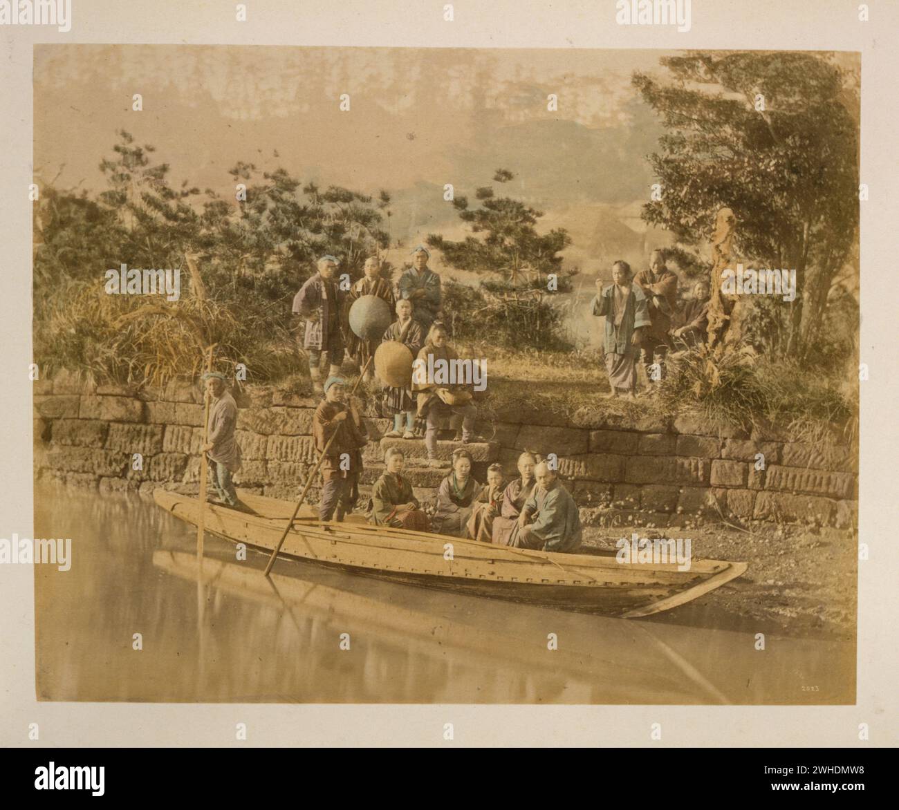 Mehrere Personen posierten für ein Porträt in einer Fähre und standen am Ufer eines Flusses am Terminal... Japan handkoloriert mit Aquarell Fotografie Print um die 1870er Jahre Stockfoto