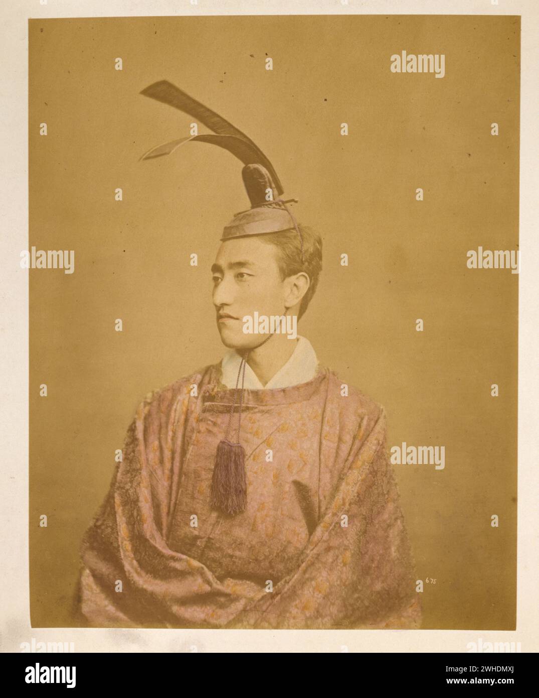 Gerichtsbeamter trägt ein Kanmuri. Das Foto zeigt ein halblanges Studio-Porträt eines Mannes, der einen Kanmuri (oder Kammuri) trägt, einen kronenähnlichen Hut, der von Adligen und/oder Hofbeamten getragen wird... Japan handkoloriert mit Aquarellfotographik Print um 1870er Jahre Stockfoto