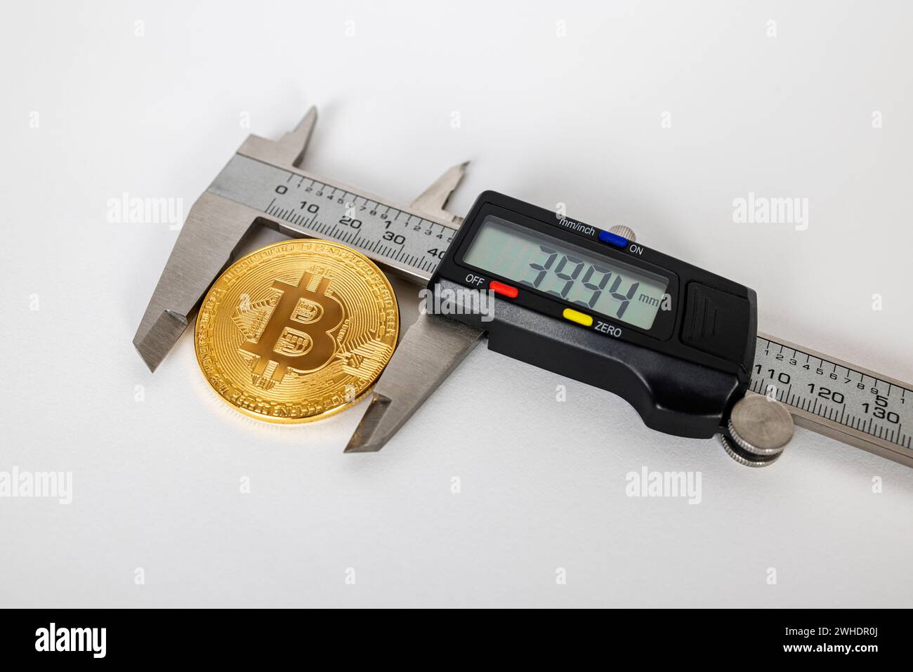Elektronischer Messschieber misst den Durchmesser einer Bitcoin-Münze, weißer Hintergrund, Stockfoto