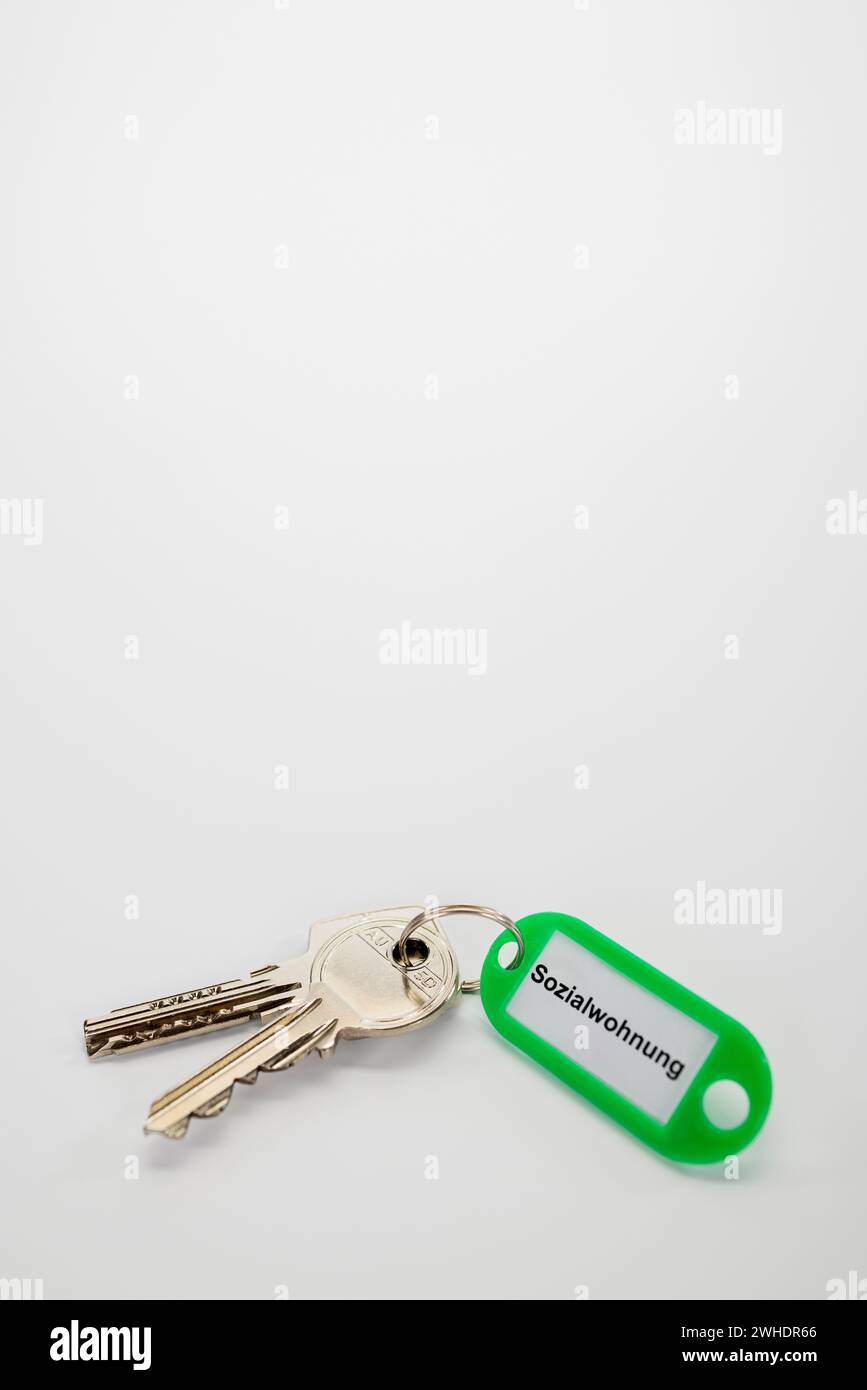 Schlüsselanhänger mit grünem Schlüsselanhänger, mit Aufschrift ëSozialwohnungë, gebohrter Schlüssel, weißer Hintergrund, Stockfoto