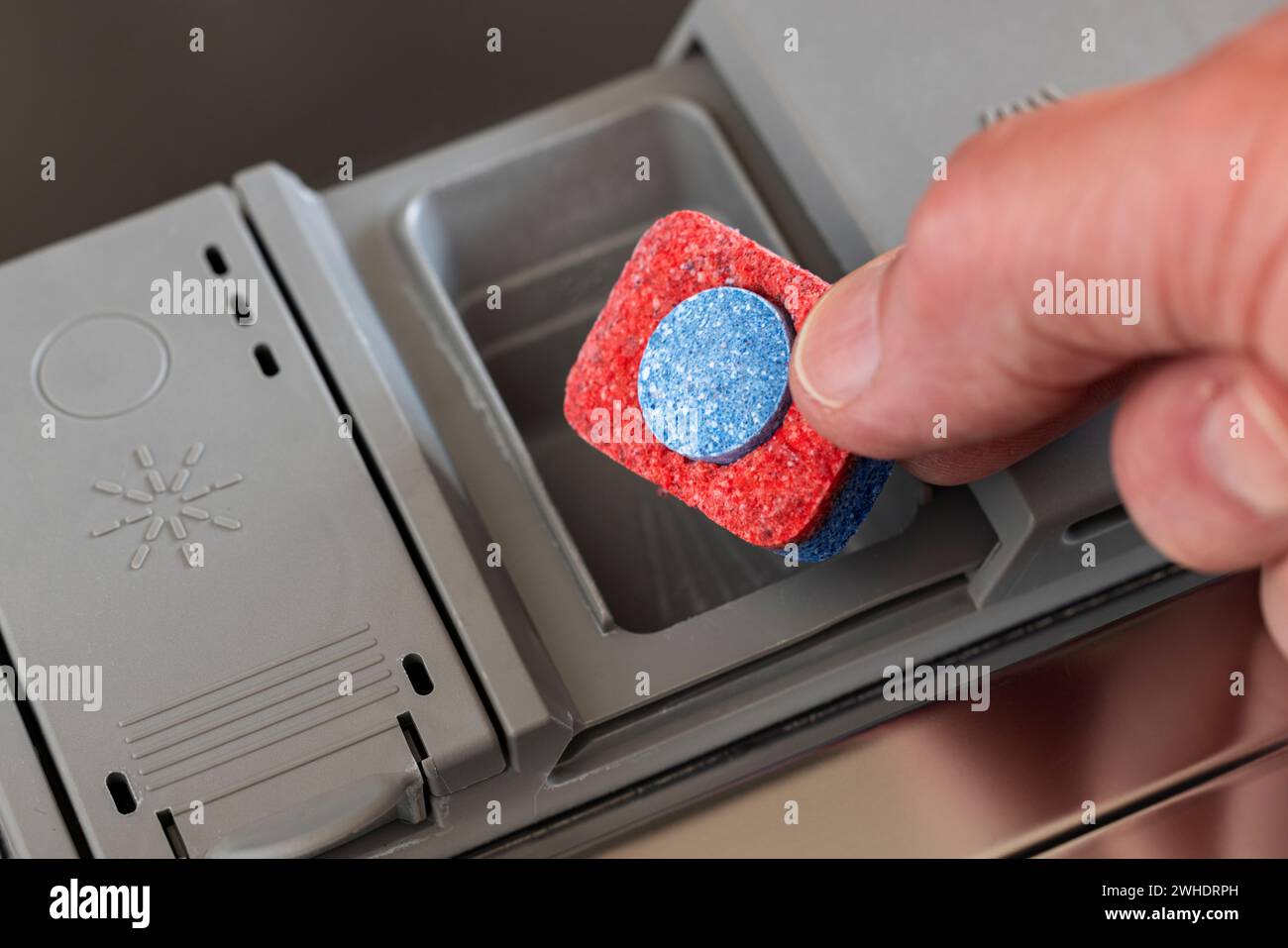 Die Hand des Mannes setzt den Reinigungsstab in die Dosierkammer, Detail, Geschirrspüler, Stockfoto