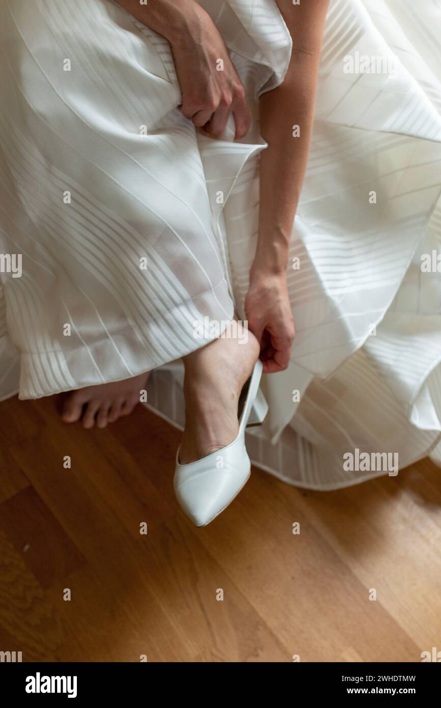 Braut zieht Schuhe an, Hochzeitskleid, Detail Stockfoto