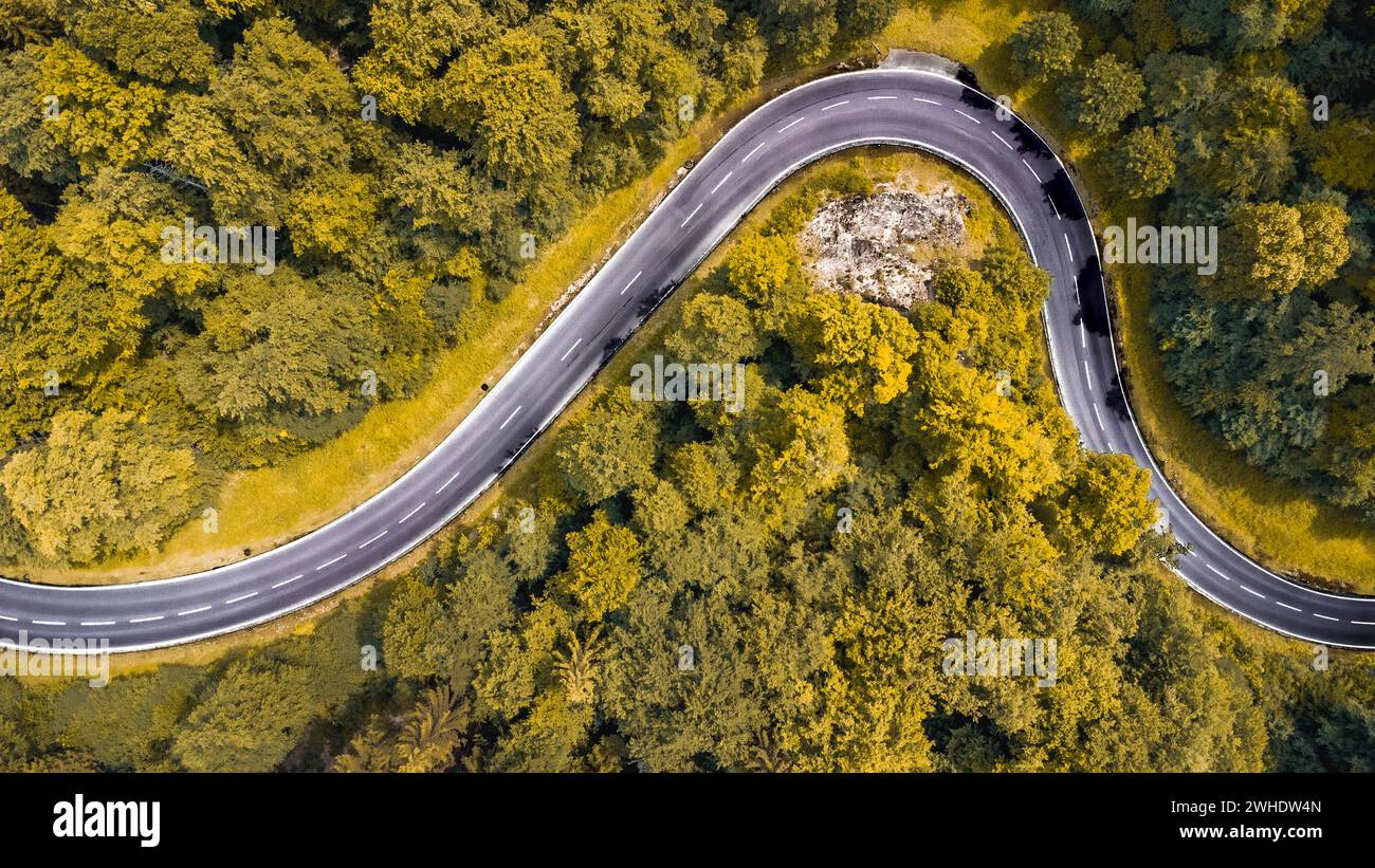 Luftaufnahme einer kurvenreichen Passstraße im Naturpark Altmühltal in Oberbayern. Die Straße schlängelt sich malerisch durch einen sommerlich gemischten Laubwald an einem Felsvorsprung vorbei Stockfoto