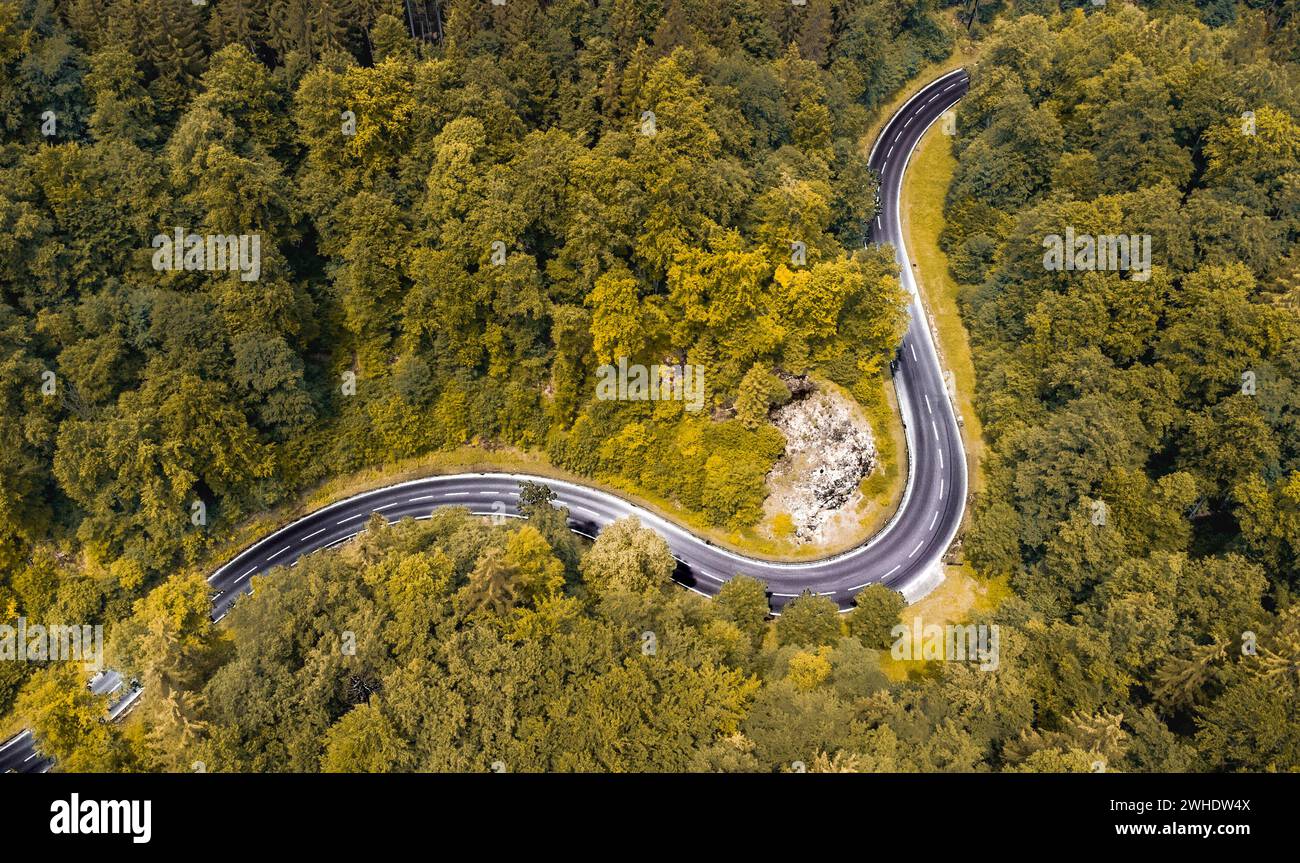Luftaufnahme einer kurvenreichen Passstraße im Naturpark Altmühltal in Oberbayern. Die Straße schlängelt sich malerisch durch einen sommerlich gemischten Laubwald an einem Felsvorsprung vorbei Stockfoto