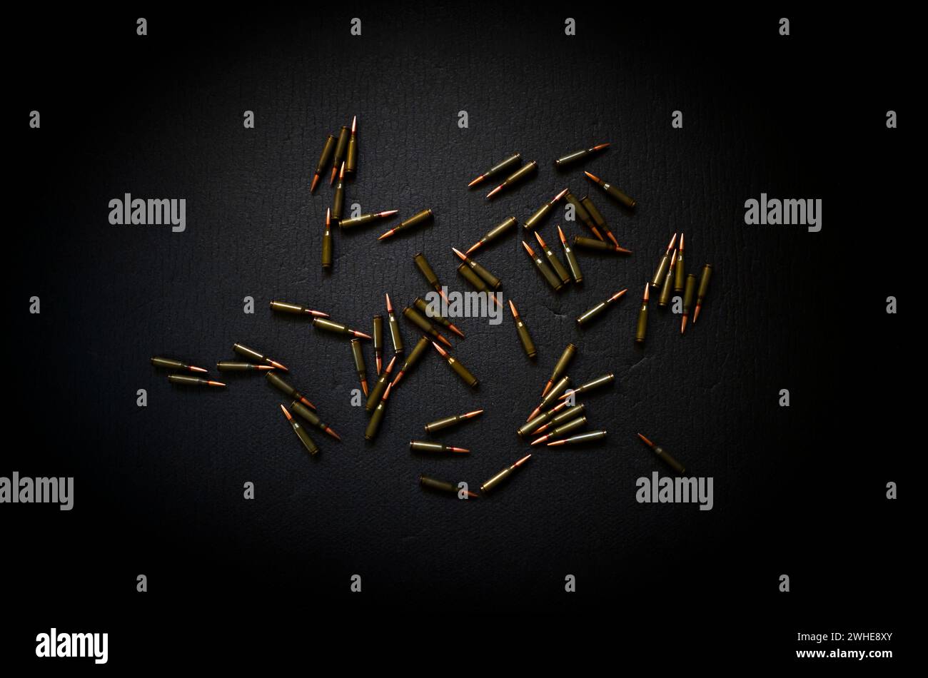 Auf einer dunklen Oberfläche verstreut sind Kugeln, Patronen für ein Kalaschnikow-Sturmgewehr. Stockfoto