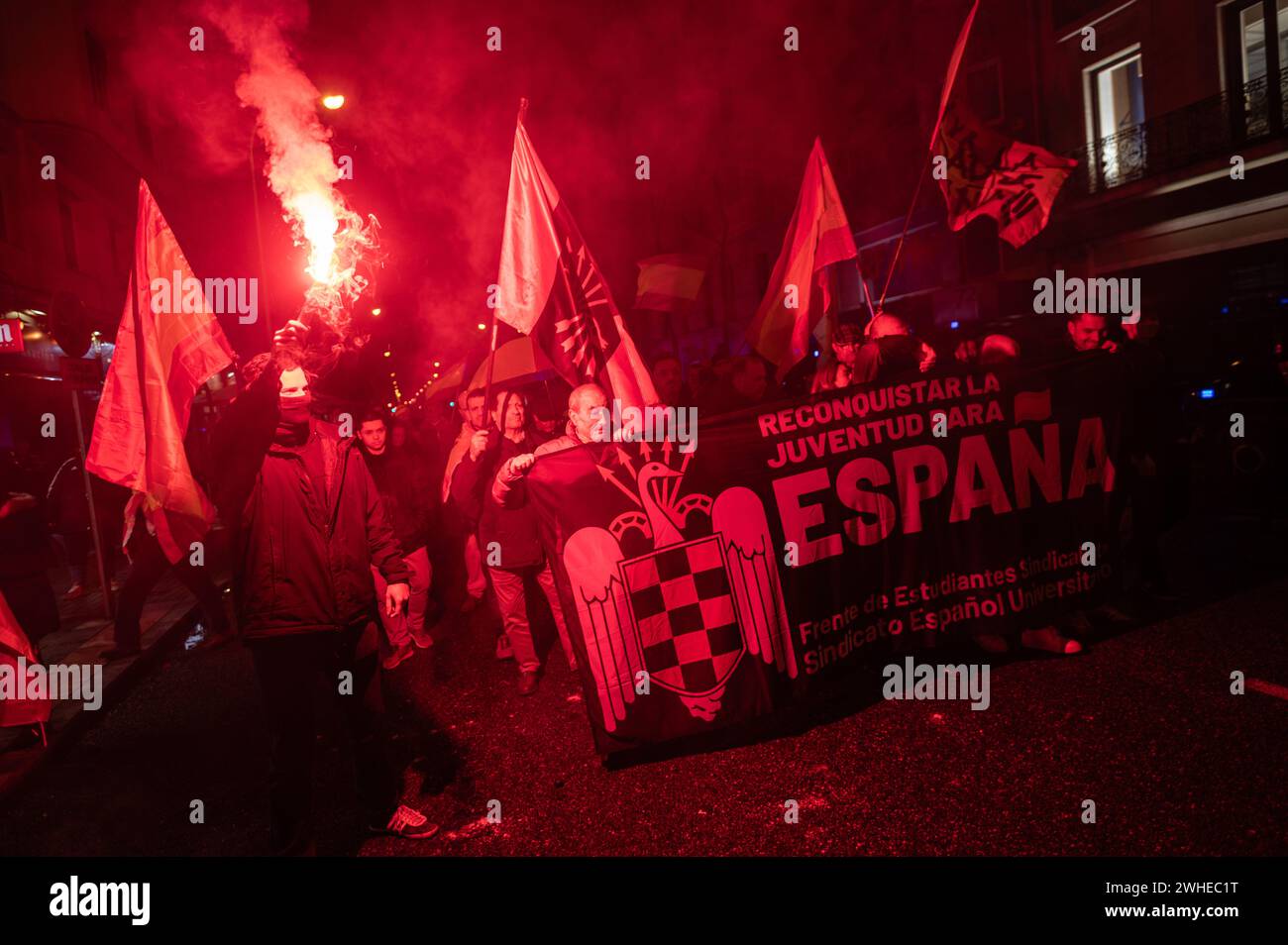 Madrid, Spanien. Februar 2024. Menschen mit einem Banner, die bei einer Demonstration der spanischen Falange vor dem Hauptquartier der sozialistischen Partei PSOE in der Ferraz-Straße mit Flares protestieren. Die rechtsextreme Gruppe Falange marschierte unter dem Slogan „mit dem Regime von 78“ mit einer Kundgebung zum Gedenken an Matias Montero, einen 1934 getöteten Studenten. Quelle: Marcos del Mazo/Alamy Live News Stockfoto