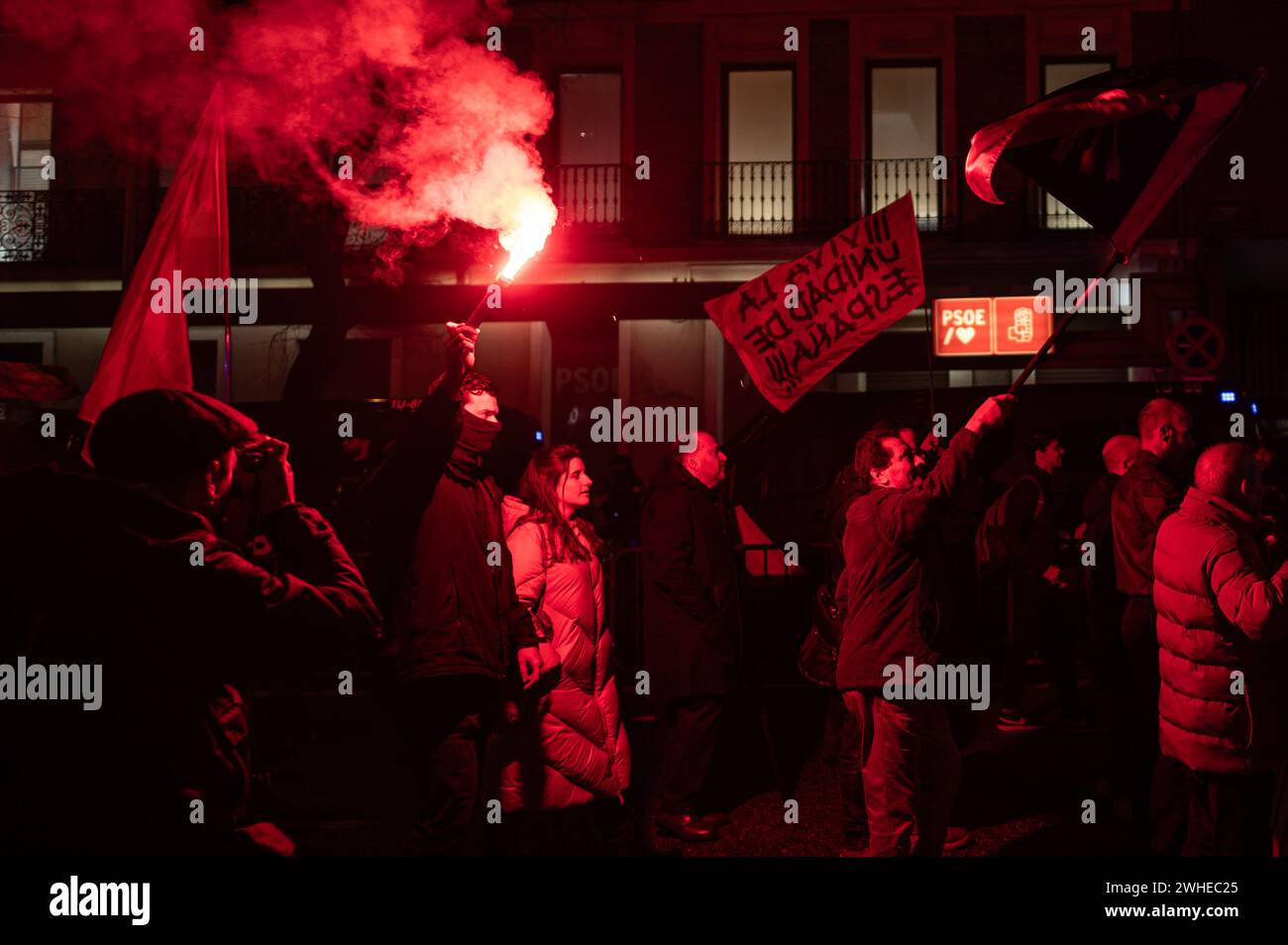 Madrid, Spanien. Februar 2024. Menschen protestieren mit Flares während einer Demonstration der spanischen Falange vor dem Hauptquartier der sozialistischen Partei PSOE in der Ferraz-Straße. Die rechtsextreme Gruppe Falange marschierte unter dem Slogan „mit dem Regime von 78“ mit einer Kundgebung zum Gedenken an Matias Montero, einen 1934 getöteten Studenten. Quelle: Marcos del Mazo/Alamy Live News Stockfoto