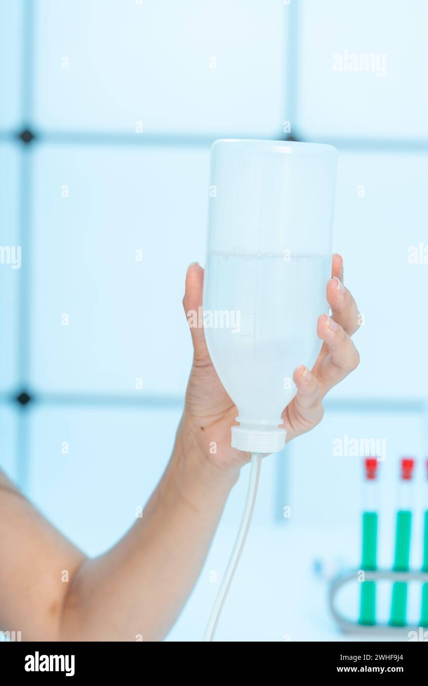 Hand hält Flüssigkeit zum intravenösen Tropfen Stockfoto