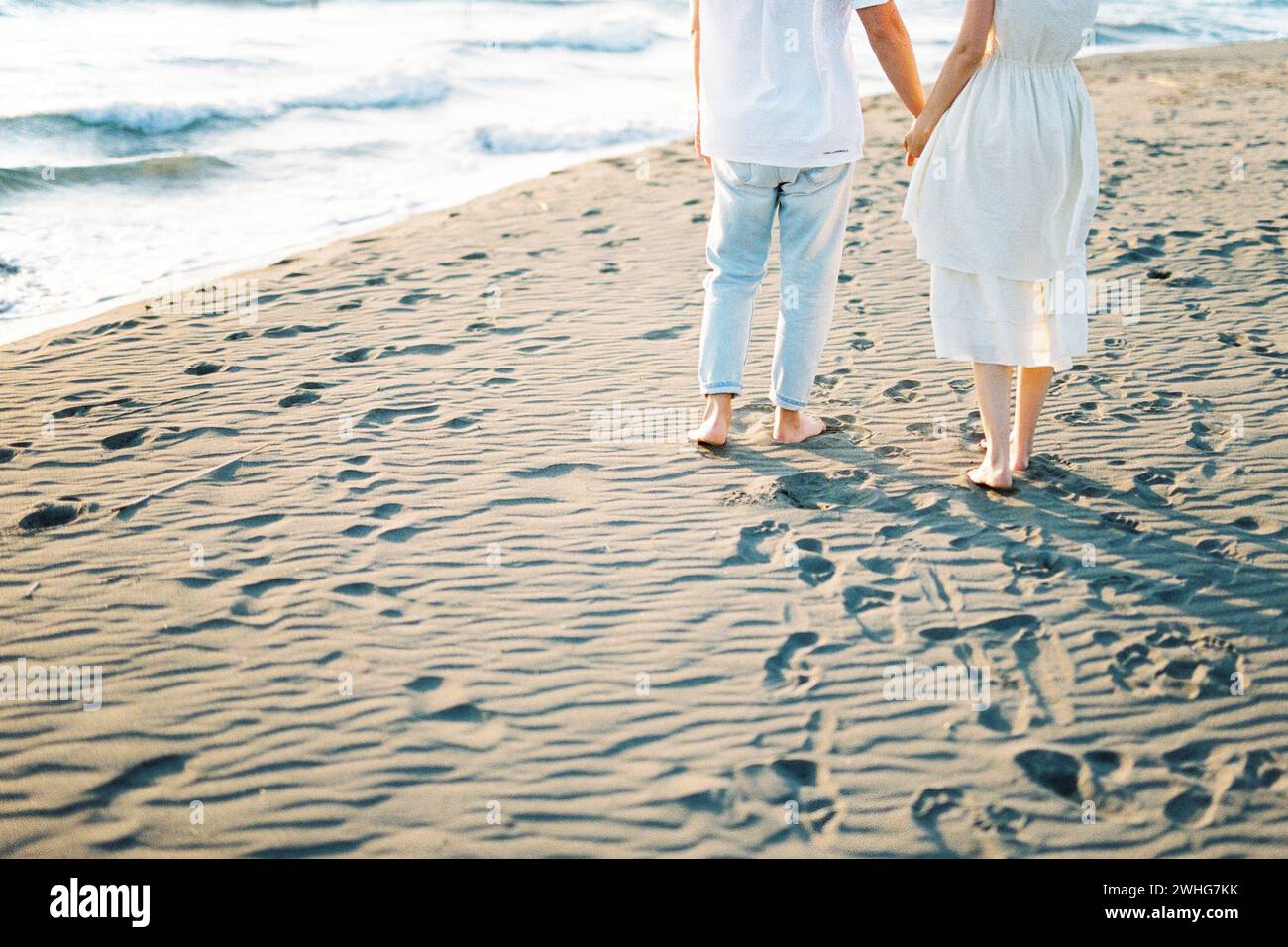 Mann und Frau stehen auf dem Sand und halten sich die Hände. Abgeschnitten Stockfoto