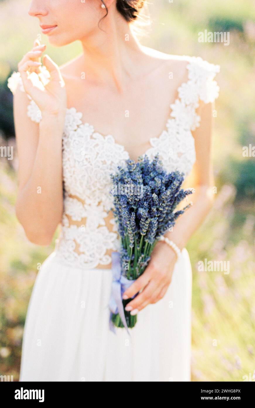 Die Braut mit einem Strauß Lavendel berührt ihr Kinn mit den Fingern. Abgeschnitten Stockfoto