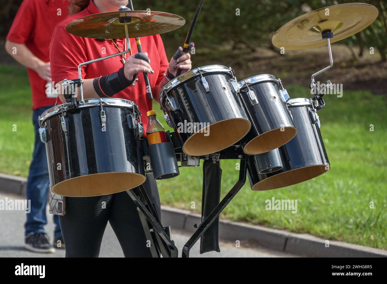 Mobiles Musikinstrument, Schlagzeug mit Schlagzeug und Zimbeln, gespielt von einer Frau in einer Marschkapelle, ausgewählter Fokus Stockfoto
