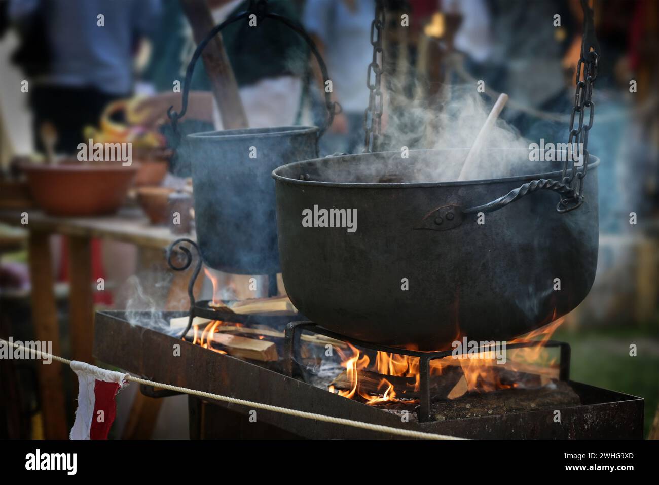 Großer Wasserkocher oder Kalkkessel mit dampfendem Eintopf über dem Feuer, Speisen für alle auf einem makellosen Festmahl im Freien, ausgewählte Fokussierung Stockfoto