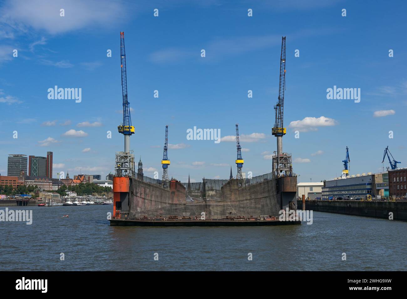 Schwimmdock mit vier Kränen, wo Schiffe im Industriegüterhafen Hamburg repariert werden, Stadt im Hintergrund, blaue SK Stockfoto