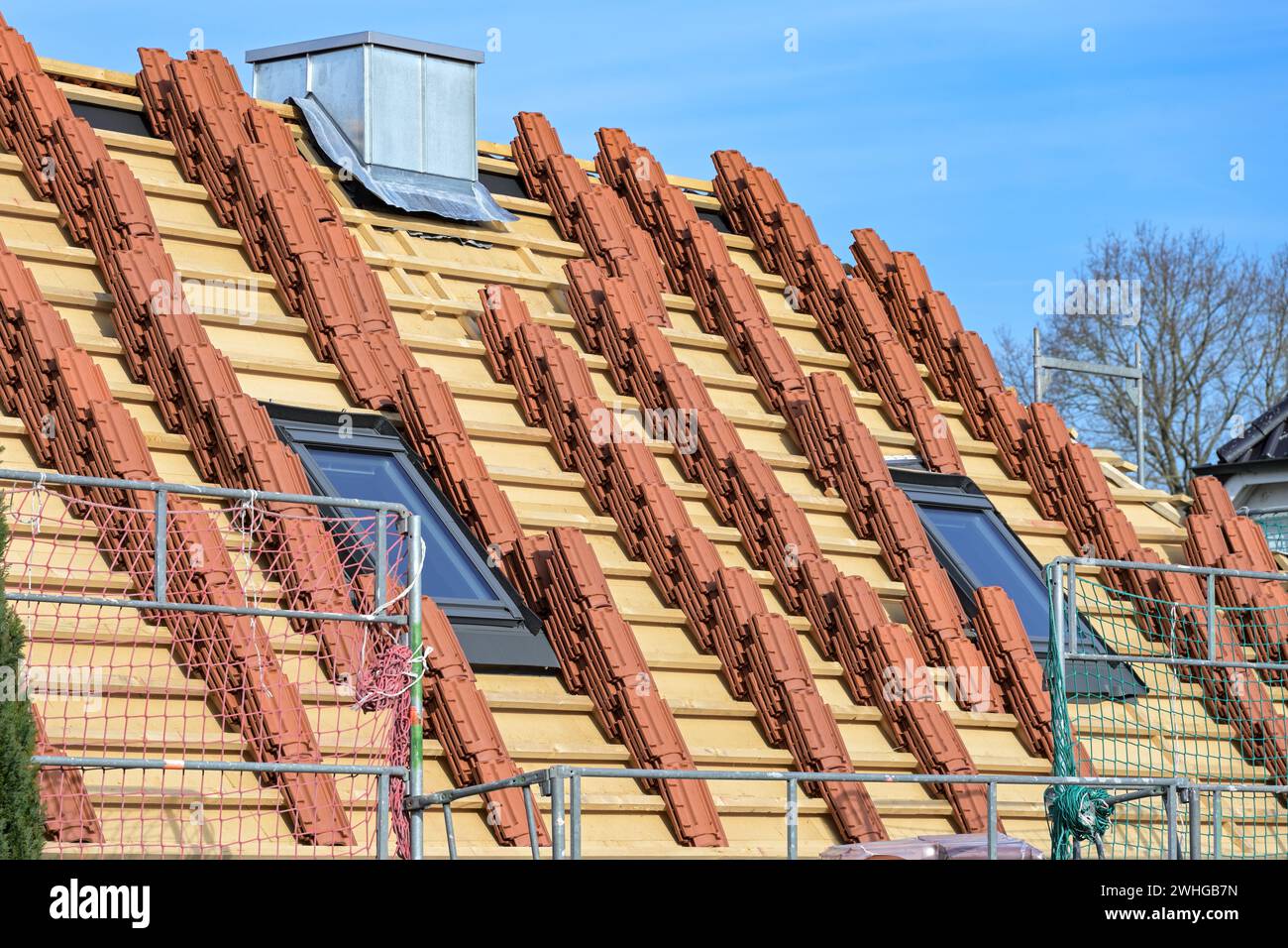 Lehmbachziegel auf dem Dach eines Wohnhauses zur Vorbereitung der Dachüberdachung auf einer Baustelle gestapelt, blauer Himmel Stockfoto