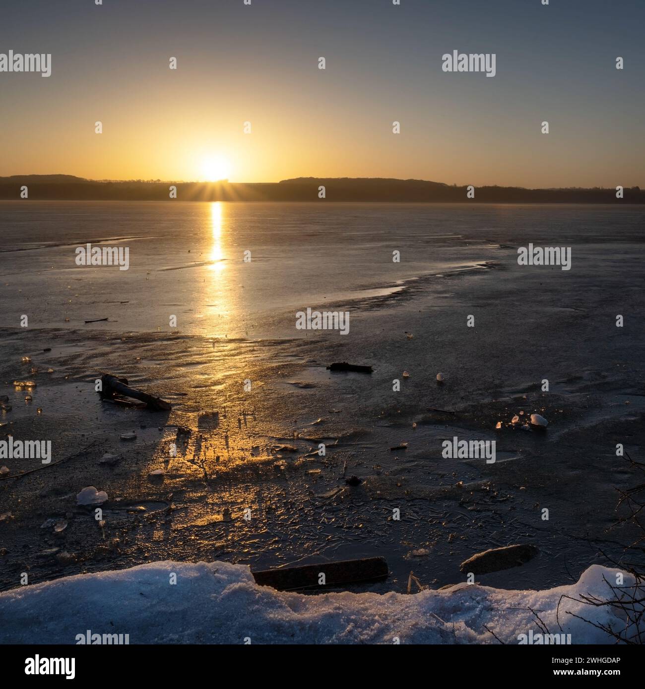 Sonnenaufgang über einem gefrorenen See mit Eisstücken und Spiegelung, Naturlandschaft mit Kopierraum, ausgewählter Fokus Stockfoto