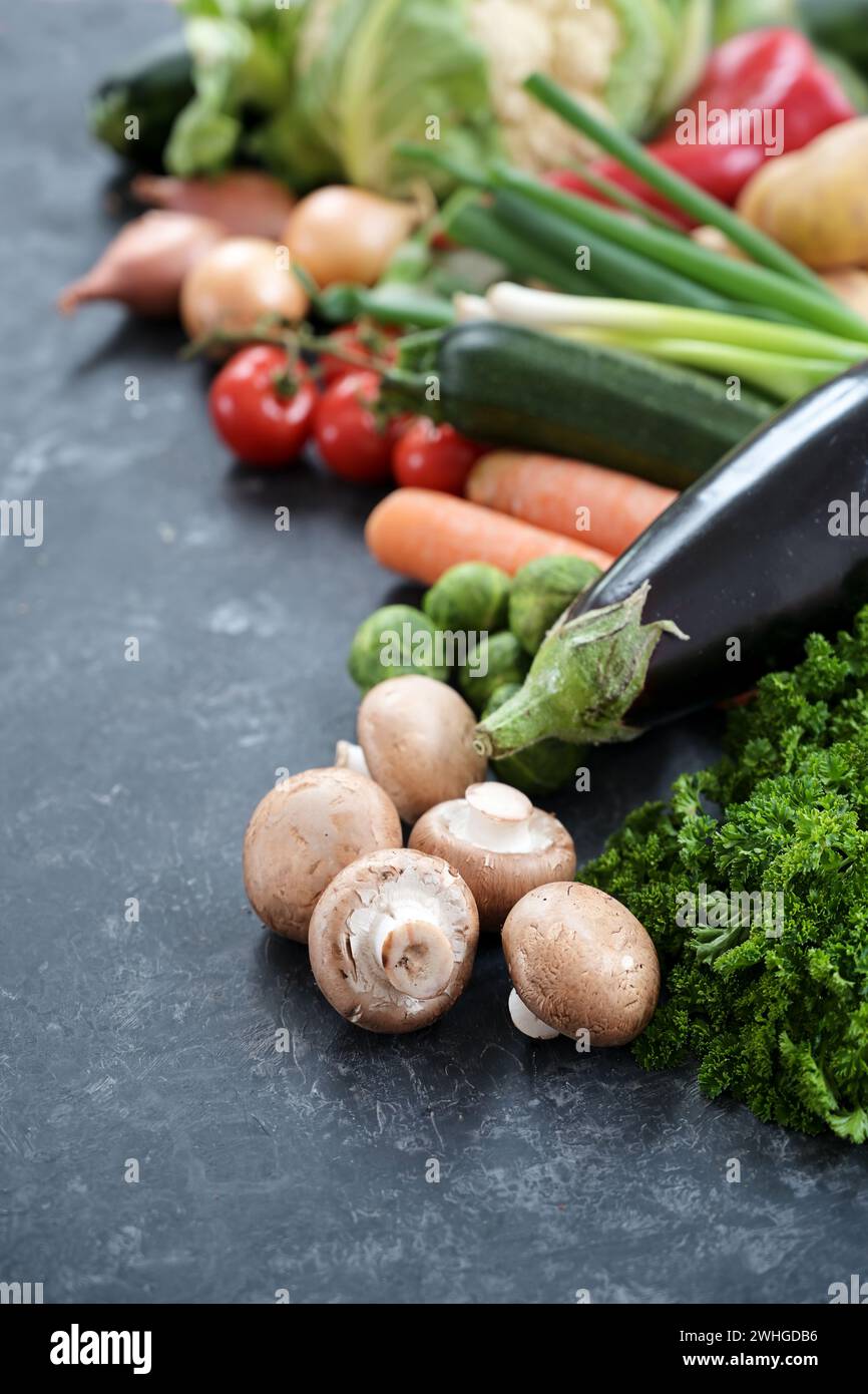 Jede Menge frisches Gemüse verschiedener Sorten auf einer dunkelgrauen Schieferoberfläche, gesundes Lebensmittelkonzept für eine ausgewogene Ernährung, Copy Spac Stockfoto