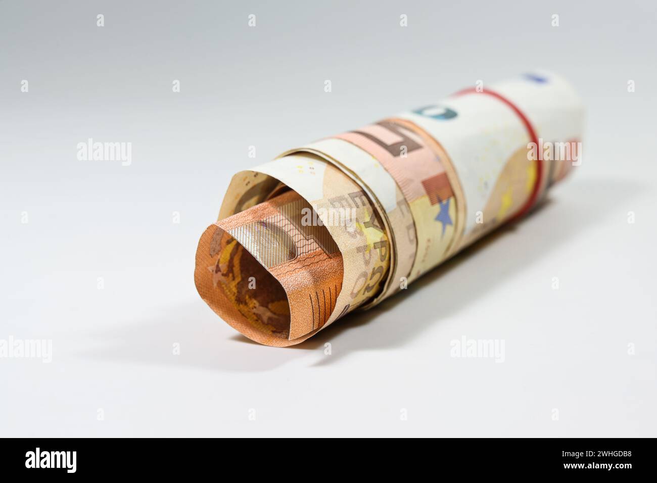 Rund 50 Euro-Banknoten wurden zu einer kleinen Rolle auf hellem Hintergrund mit Kopierraum und ausgewähltem Fokus zusammengerollt Stockfoto