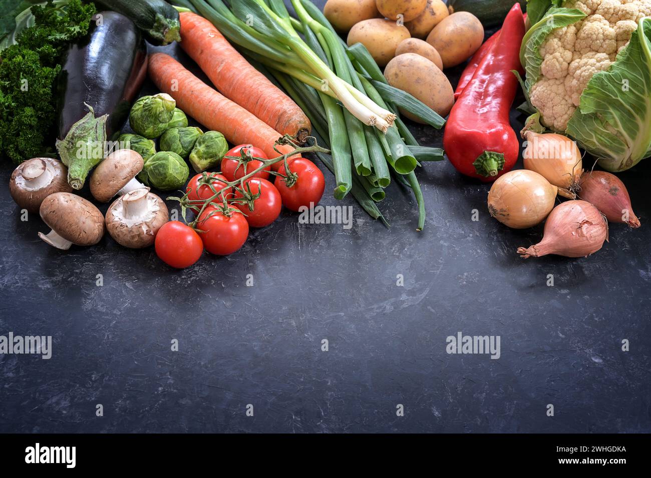 Verschiedene Gemüse auf einem dunkelgrauen Schieferhintergrund, gesundes Lebensmittelkonzept für Fitness und Gewicht verlieren Diät, Kopierraum Stockfoto