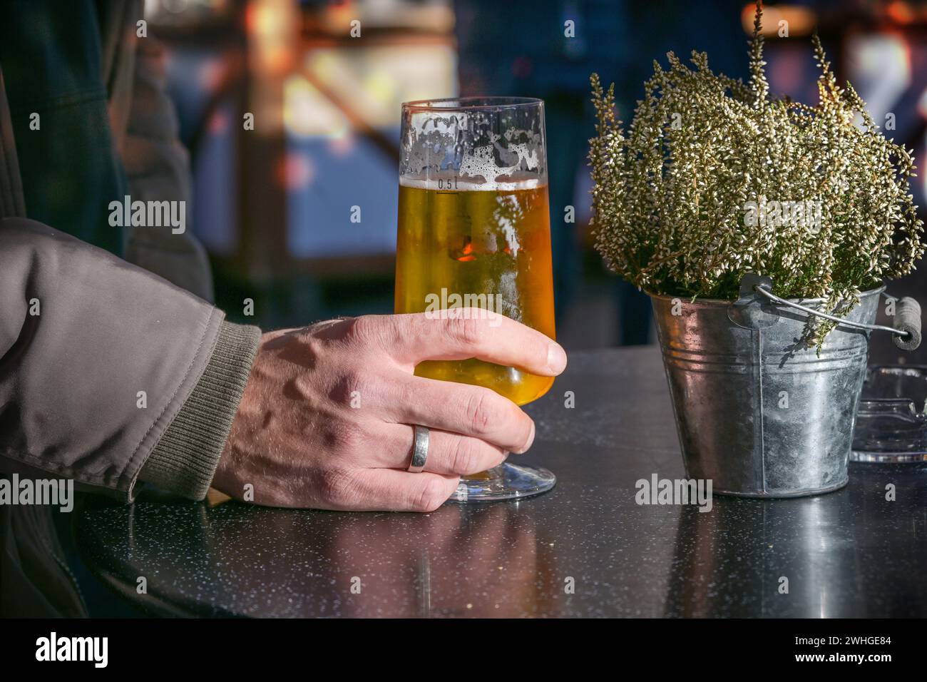 Hand eines Mannes, der ein Bierglas auf einem Tisch im Freien auf einem traditionellen Wintermarkt hält, ausgewählter Fokus Stockfoto