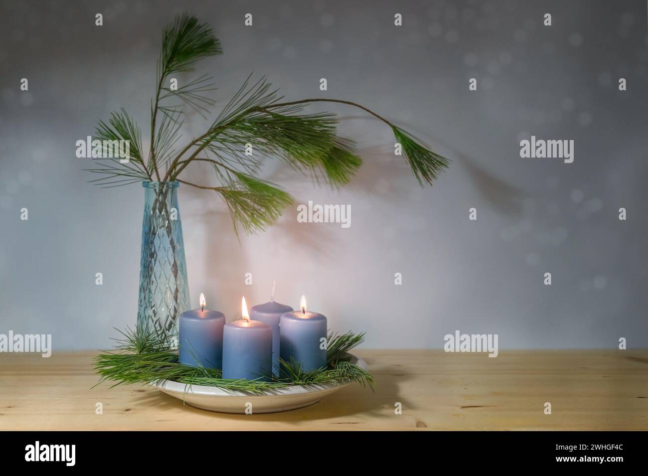 Blaue Kerzen, drei für den dritten Advent angezündet, und eine Vase mit Tannenzweigen, moderne Dekoration in der Weihnachtszeit, Copy Spa Stockfoto
