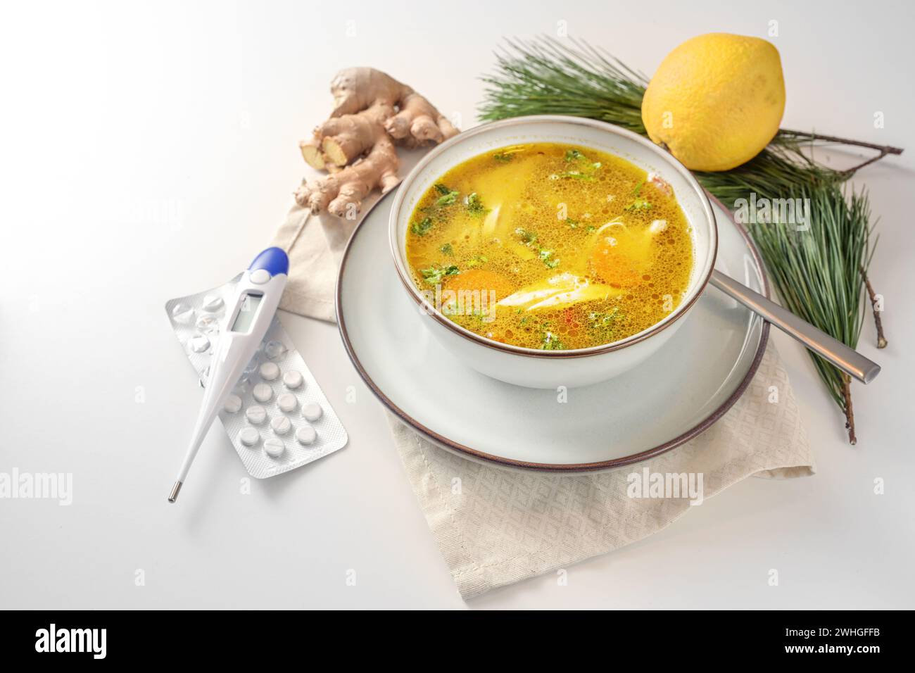 Bleiben Sie gesund in der Kälte- und Grippesaison mit Hühnersuppe, Ingwer und Zitrone als Hausmittel, Faserthermometer und Tabletten für Stockfoto