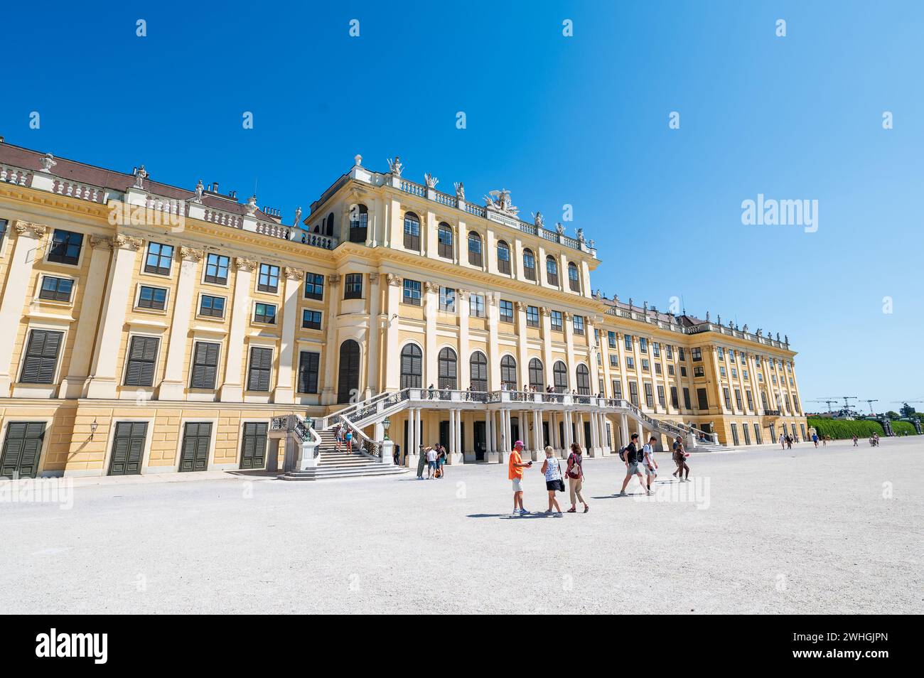 Wien, Österreich - 12. August 2022: Das Wiener Schloss schönbrunn erhebt sich über einem belebten Stadtplatz, während sich die Menschen unter dem Sommerhimmel versammeln und die Gr. Bestaunen Stockfoto