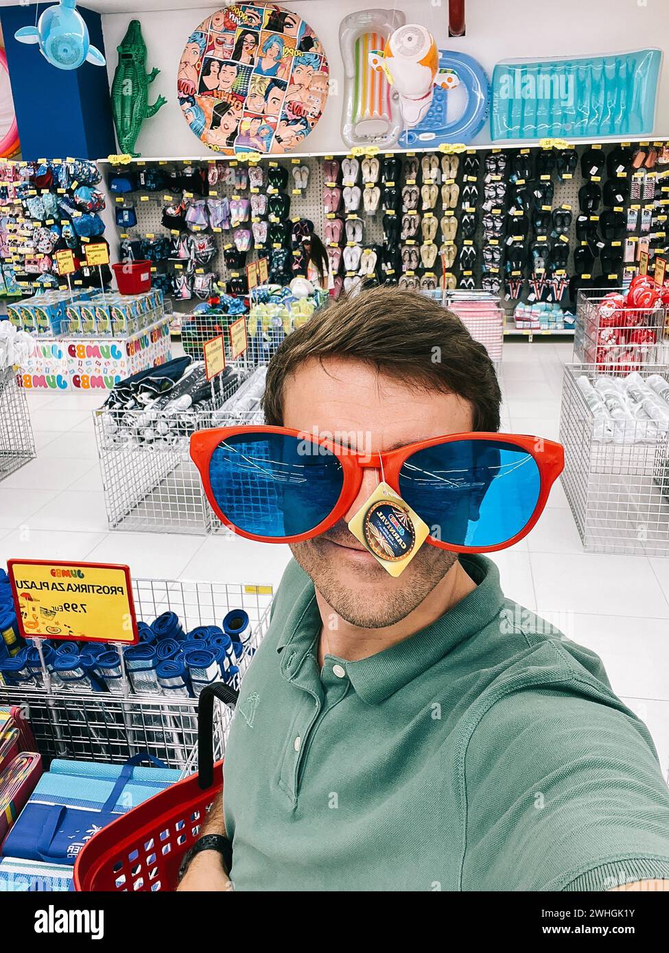 Ein Mann probiert eine riesige Sonnenbrille in einem Supermarkt Stockfoto
