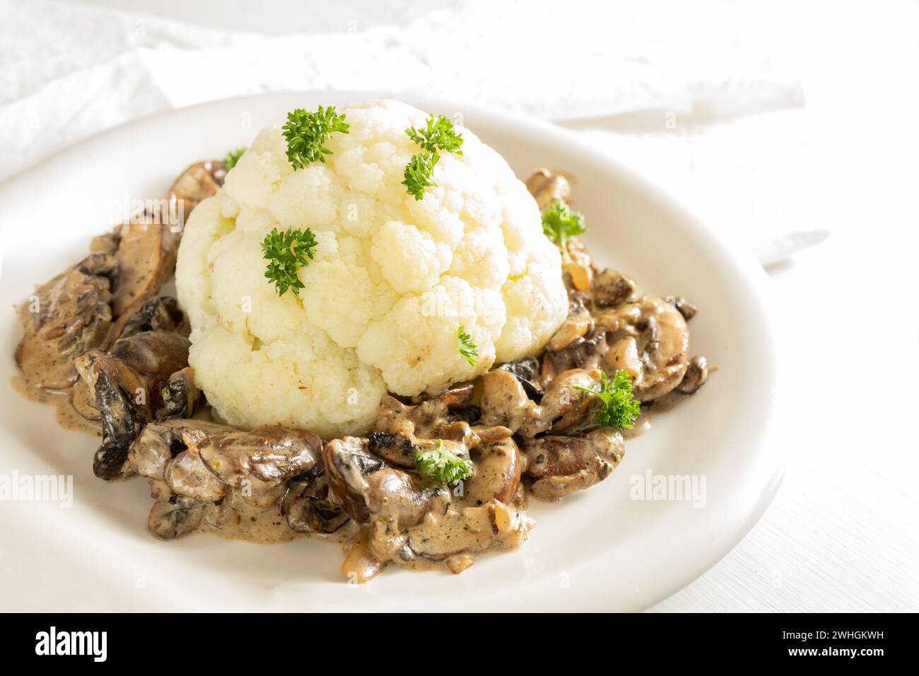 Blumenkohl mit Pilzragout und Petersiliengarnitur, gesundes vegetarisches Gericht aus Gemüse, Kopierraum, ausgewählter Fokus Stockfoto