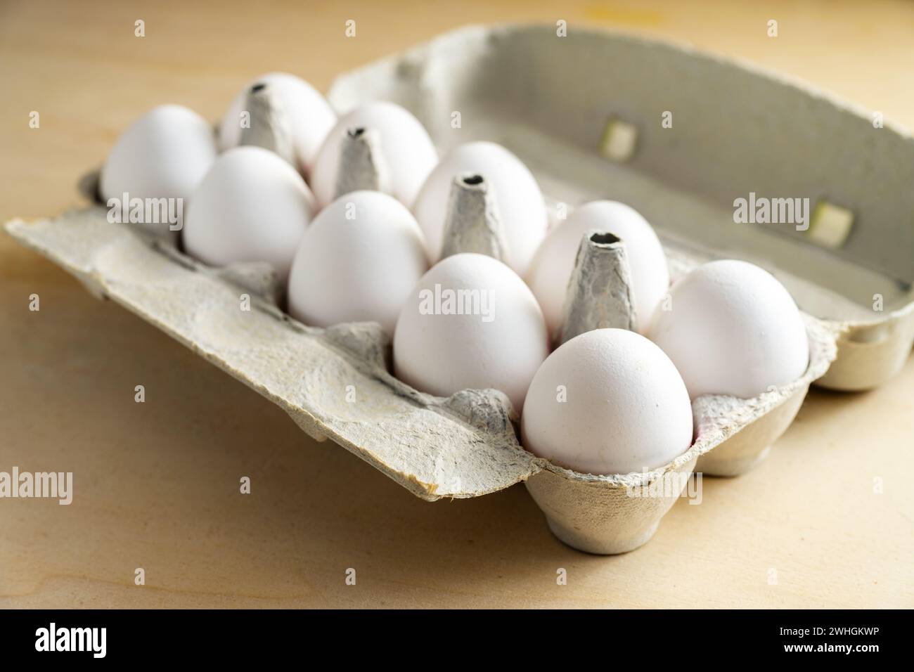 Zehn frische weiße Eier in einem Karton auf einem Holztisch, Essen und Osterkonzept, ausgewählter Fokus Stockfoto