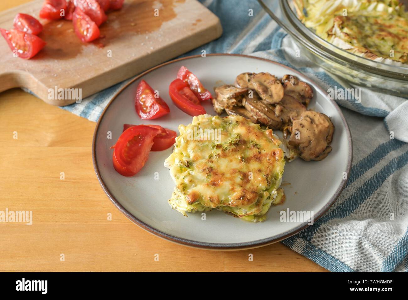 Gratinierter Chinakohl mit Pilzen und Tomaten, gesundes vegetarisches Gericht auf einem Holztisch, Kopierraum, ausgewählter Fokus Stockfoto