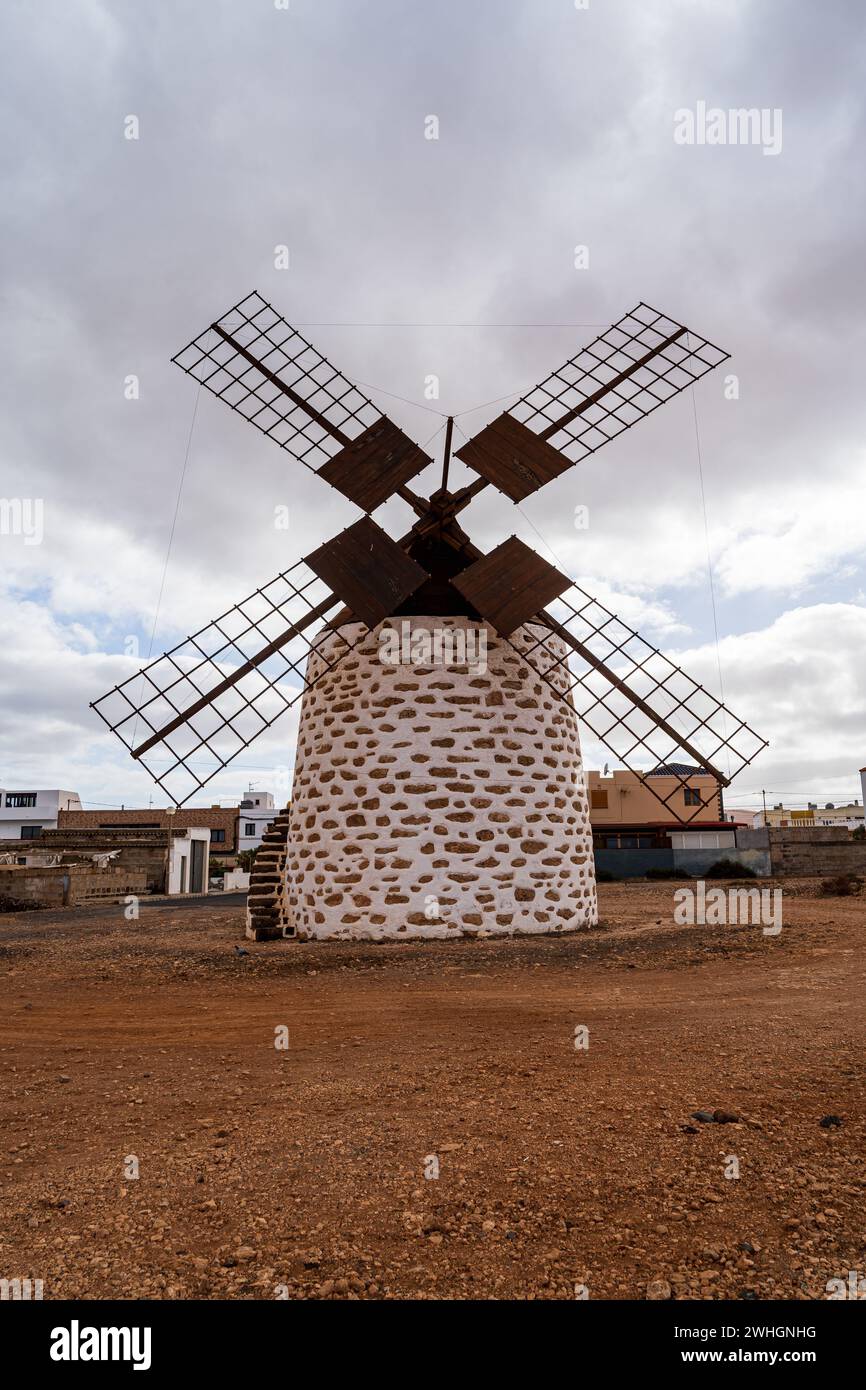 Eine traditionelle Windmühle mit Steinfuß und Holzklingen vor einem bewölkten Himmel in Valles de Ortega, Fuerteventura. Stockfoto
