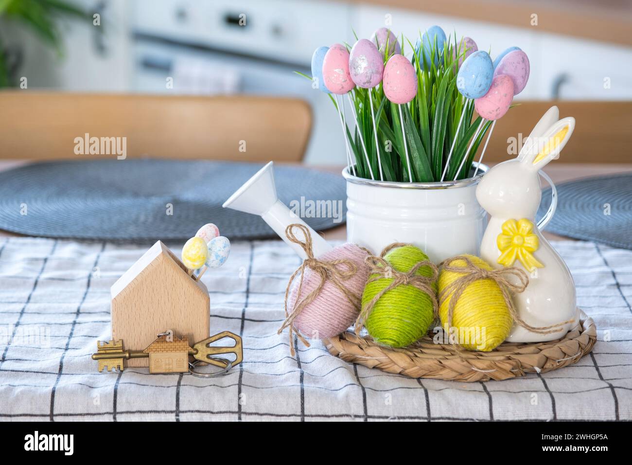 Schlüssel zum Haus eines gemütlichen Hauses mit Osterdekor mit Hase und Eiern auf dem Tisch der Küche. Bauen, entwerfen, Projekt, Umzug in neue h Stockfoto
