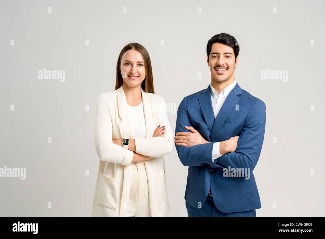 Ein professionelles männliches und weibliches Team, in eleganter Geschäftskleidung, mit überkreuzten Armen nebeneinander. Dieses Bild zeigt den kooperativen Geist und die strategische Planung Stockfoto