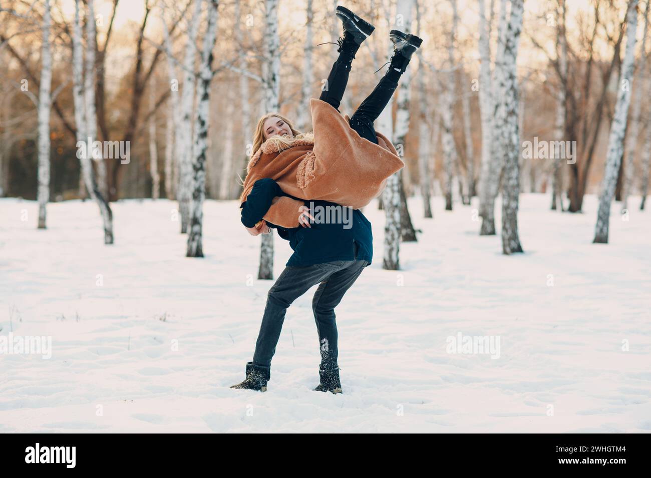 Liebevolles junges Paar, das im Winterwaldpark spielt und Spaß hat Stockfoto