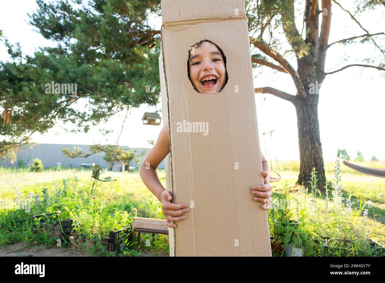 Das Kind tanzt und täuscht in einem Box Kostüm herum - runder Ausschnitt für Gesicht und Hände. Zieht in ein neues Haus, Kind Stockfoto