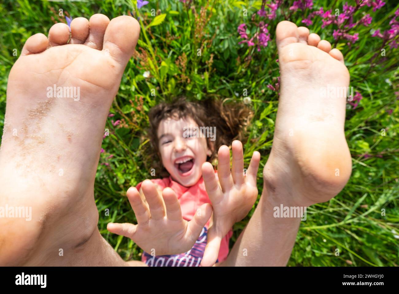 Porträt eines im Sommer im Gras liegenden Mädchens mit Wildblumen und Fersen und Palmen. Sommerzeit, Freiheit Stockfoto
