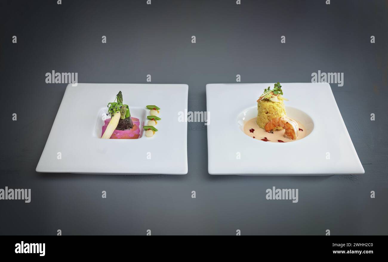 Zwei Gerichte eines modernen Gourmetmenüs, Spargel in Nori-Blatt mit Rote-Bete-Sauce, Fischgericht aus Safranrisotto mit Garnelen und Stockfoto