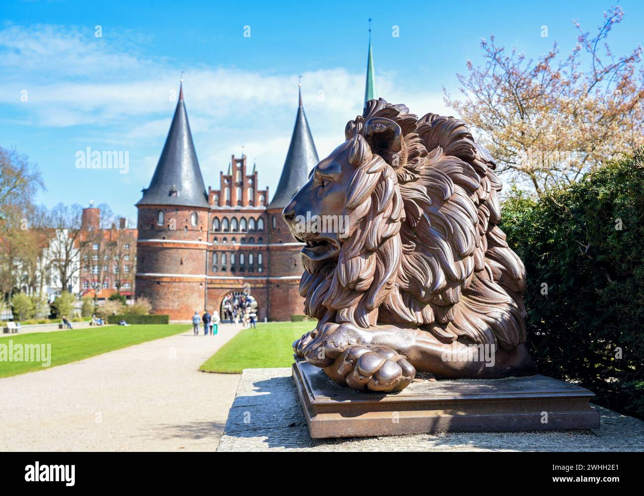 Löwenstatue von eisernen Wachen das Lubecker Holstentor oder Holstentor, historisches Wahrzeichen und Touristenattraktion unter blauem Himmel, s Stockfoto