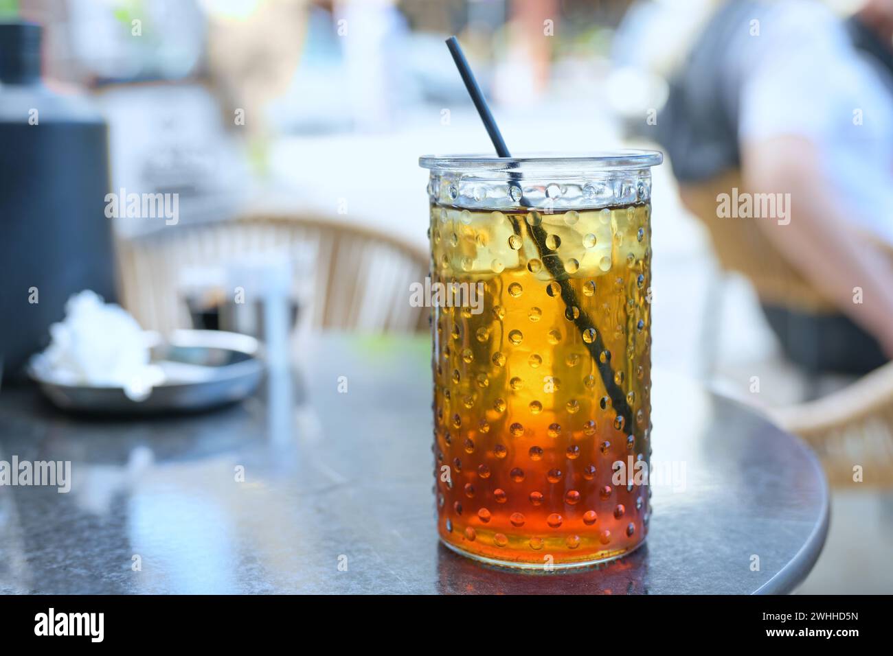 Erfrischender Eistee mit Zitronensirup und Trinkhalm in einem Glas in einem Straßencafé im Sommer, ausgewählter Fokus Stockfoto