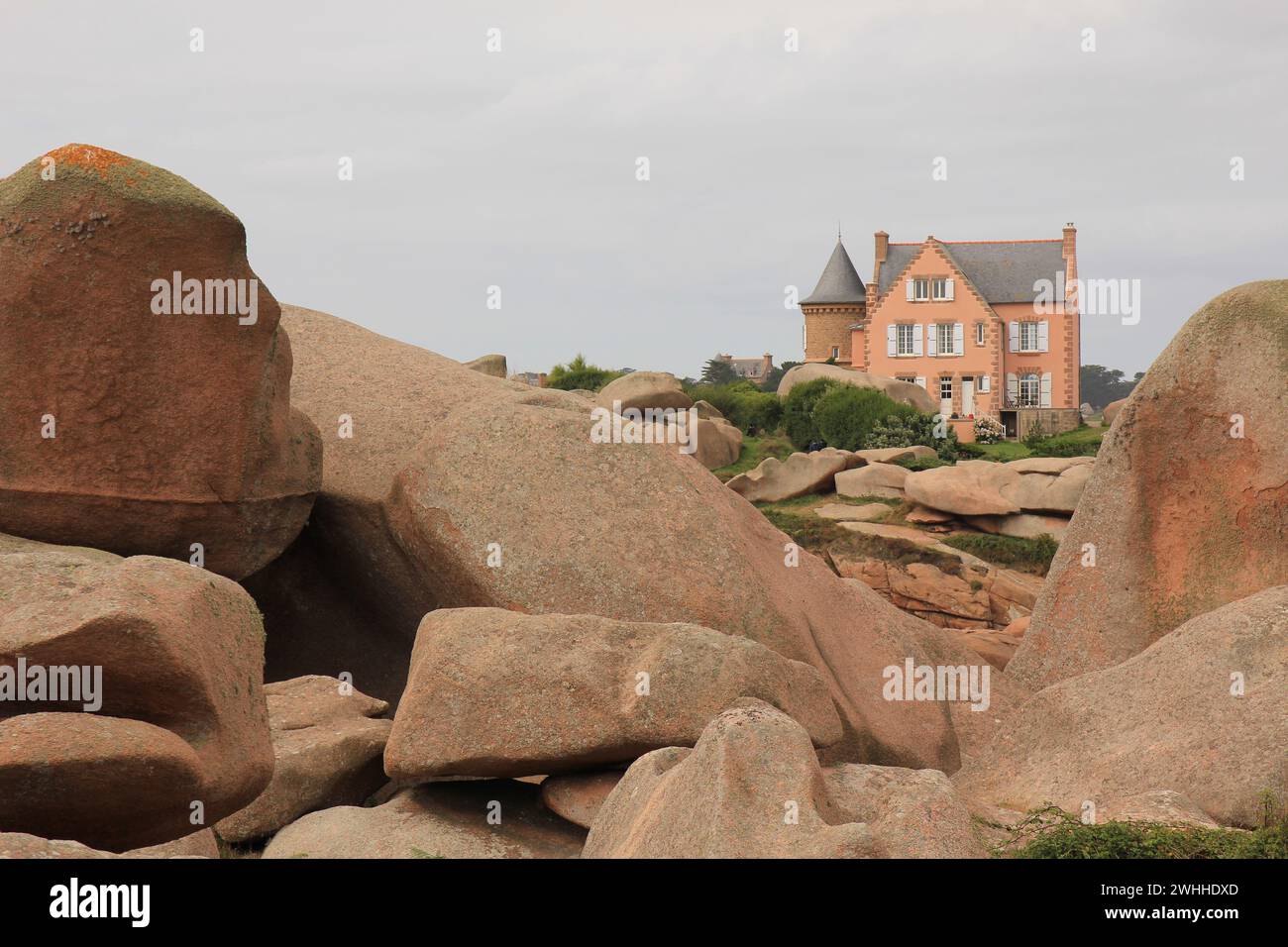 Granitfelsen und alte Villa, Granit Rose Coast, Frankreich. Stockfoto