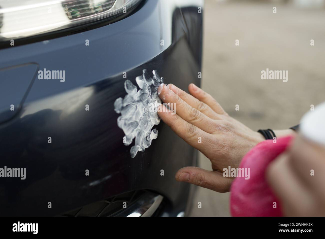 Handarbeit zur Reinigung des Autos mit manueller Polierpaste mit Mikrofasertuch, das den Lacklack des Parkleiters aufzeigt Stockfoto