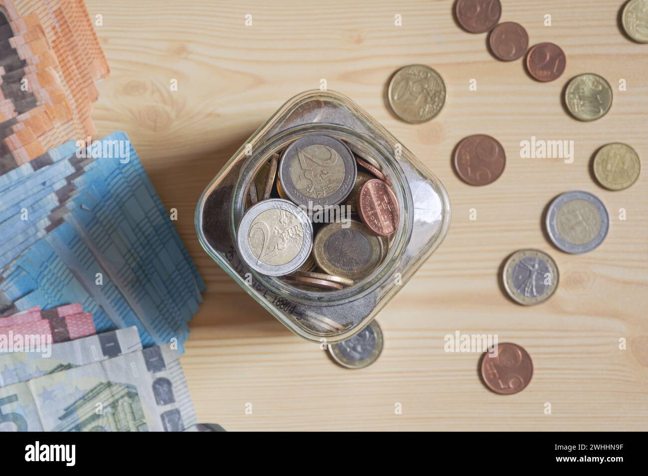 Altersvorsorge in Euro, Münzen in einem Glas und Geldscheine in Papierform auf dem Schreibtisch, Draufsicht Stockfoto