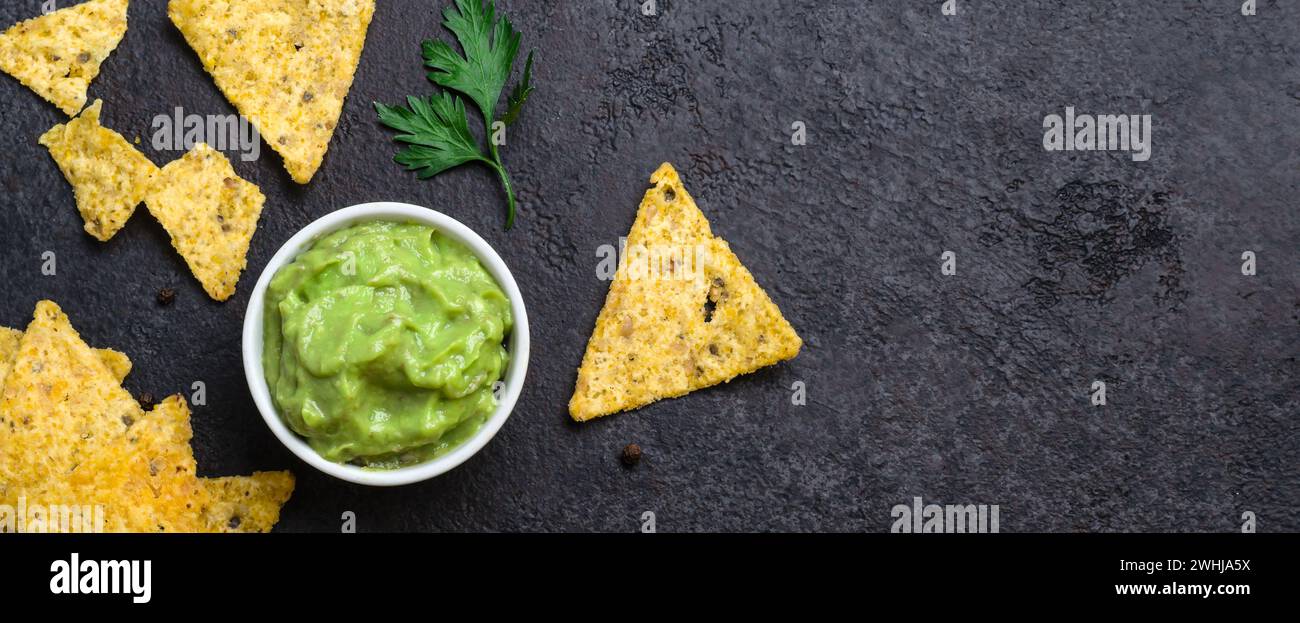 Traditionelles mexikanisches Essen Guacamole und Maischips auf schwarzem Hintergrund. Bannerformat Stockfoto