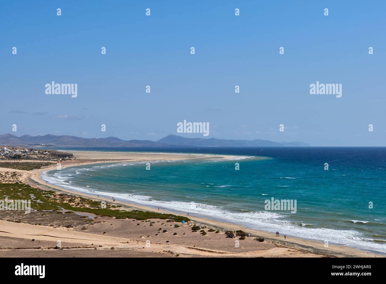 Der Atlantik in Jandia mit klarem Himmel und Bergen im Rücken und Wellen, die am Ufer brechen Stockfoto